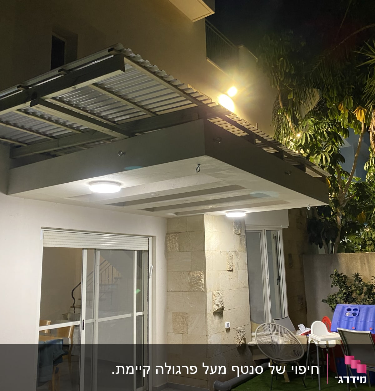 פרגולה מעץ עם תאורה מעל גינה קטנה